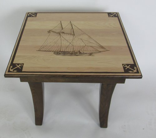 A wooden table featuring a sailboat design on the top, with decorative anchor motifs in the corners.
