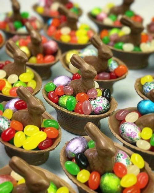 Colorful Easter baskets filled with candy and chocolate bunnies, arranged in a festive display.