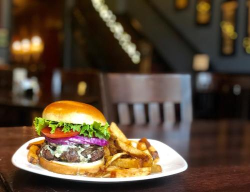 A juicy burger with lettuce, tomato, and onion, served with golden fries on a white plate in a cozy restaurant setting.