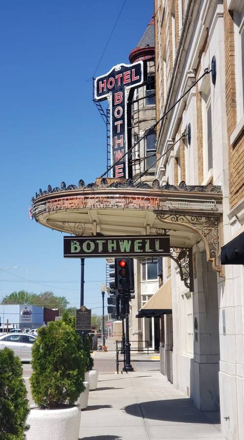 Historic Hotel Bothwell sign with ornate marquee, blue sky, and traffic light in front.
