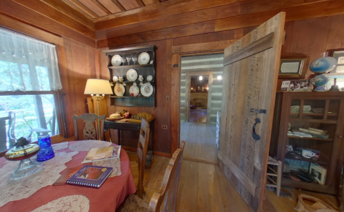 Cozy wooden interior with a dining table, vintage decor, and an open door leading to another room.