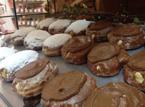 A display of donuts, some topped with powdered sugar and others with chocolate frosting, on a metal tray.