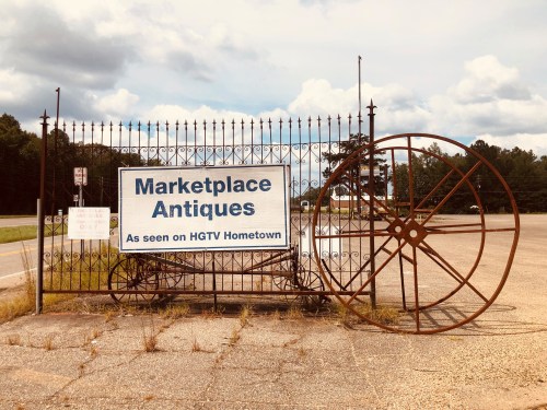Sign for Marketplace Antiques featuring a large wheel, with a note about being featured on HGTV Hometown.