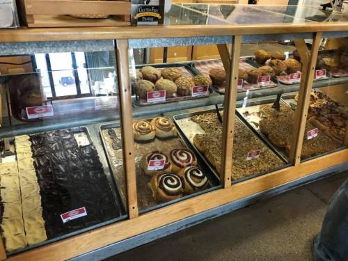 A display case filled with various baked goods, including cookies, pastries, and cinnamon rolls.