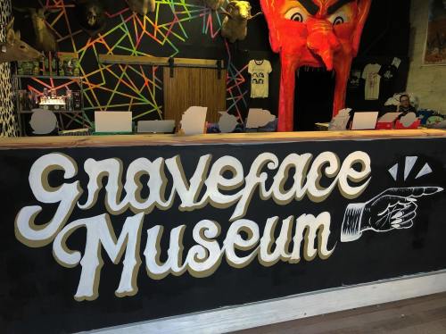 A colorful reception area of the Graveface Museum featuring a large, artistic sign and a vibrant backdrop.