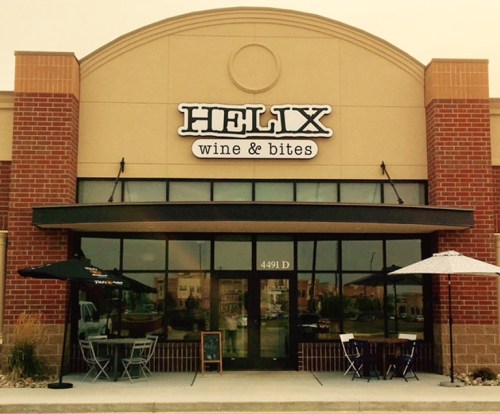 Exterior of Helix Wine & Bites, featuring a brick facade, large windows, and outdoor seating with umbrellas.