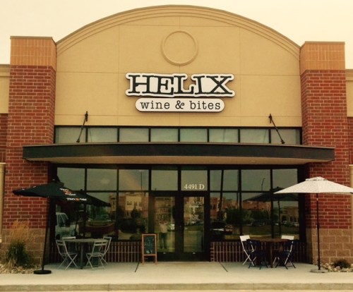 Exterior of Helix Wine & Bites, featuring a brick facade, large windows, and outdoor seating with umbrellas.