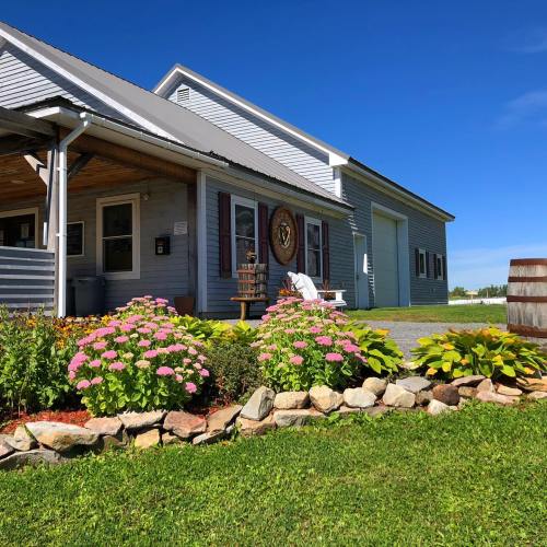 A charming blue house with a porch, surrounded by colorful flowers and greenery under a clear blue sky.