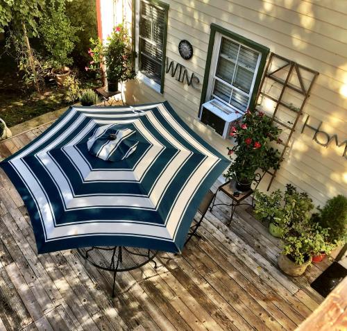A striped umbrella shades a patio table surrounded by potted plants and a cozy outdoor setting.
