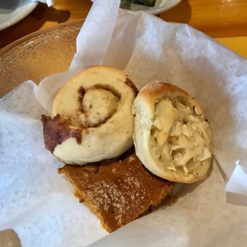 A plate with two baked goods: a cinnamon roll and a cookie, resting on parchment paper.