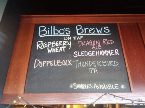 Chalkboard menu listing Bilbo's Brews on tap: Raspberry Wheat, Dragon Red Ale, Sledgehammer, Doppelbock, Thunderbird IPA.