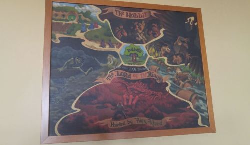 A framed artwork depicting scenes from "The Hobbit" and "The Lord of the Rings," painted by Alex Alorda.