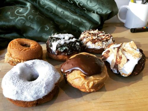 A variety of six donuts on a wooden surface, featuring different toppings like chocolate, cream, and sprinkles.