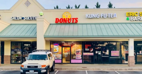 A storefront featuring a donut shop and a tea shop, with a white SUV parked outside.