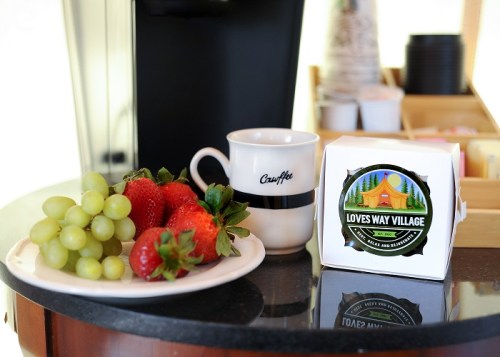A plate of strawberries and grapes next to a coffee cup and a box labeled "Love's Way Village."
