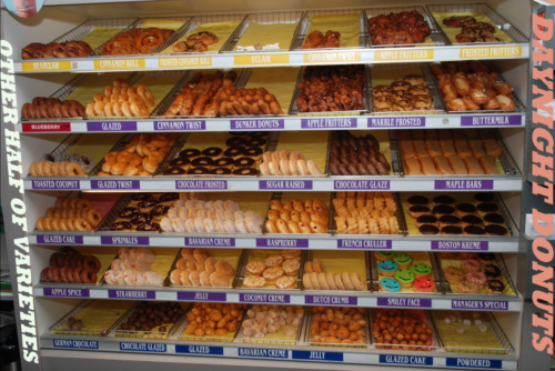 A display case filled with various donuts, including glazed, frosted, and filled varieties in an array of colors and shapes.