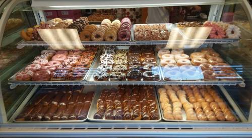 A display case filled with a variety of colorful donuts, including glazed, chocolate, and sprinkled options.