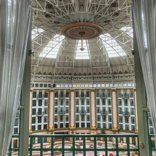 View from a balcony overlooking a grand atrium with a glass ceiling and elegant architecture.