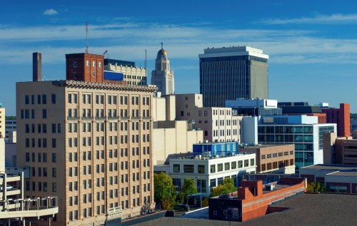 A city skyline featuring a mix of modern and historic buildings under a clear blue sky.