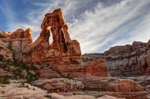 A striking rock formation with two towering pillars against a blue sky, surrounded by rugged canyon landscape.