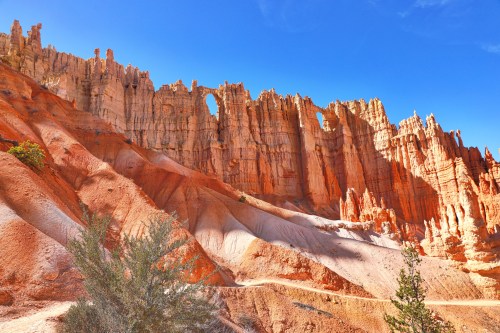 A stunning view of orange rock formations with natural arches under a clear blue sky.