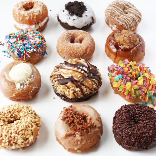 A colorful assortment of 12 donuts with various toppings, including sprinkles, chocolate, and fruit cereal.
