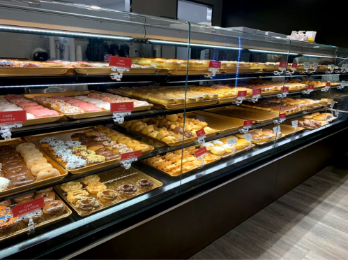 A display case filled with various pastries and donuts, showcasing colorful treats and baked goods.