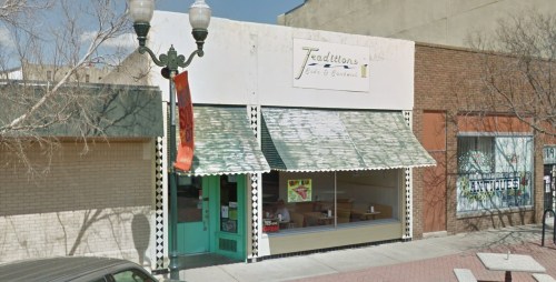 A storefront with a green awning and sign reading "Traditions," featuring large windows and a decorative entrance.