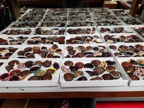 A display of assorted chocolate candies in white boxes, featuring various toppings and fillings.