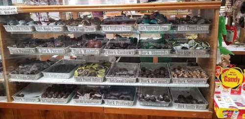 A display case filled with various types of chocolate-covered treats, including nuts, caramels, and candies.