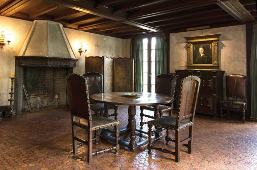A rustic dining room featuring a wooden table, chairs, a fireplace, and vintage decor on the walls.