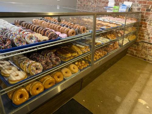 A display case filled with a variety of colorful donuts, including glazed, sprinkled, and cream-filled options.