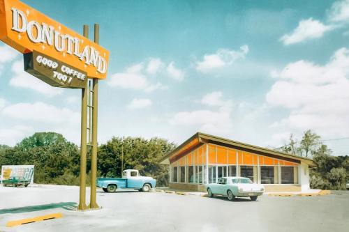A retro diner named "Donutland" with a bright sign, featuring a blue truck and a white car parked outside.