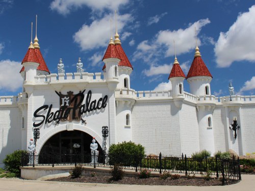A whimsical castle-like building with red turrets and white walls, featuring the sign "Skate Palace" at the entrance.