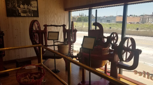 Historic machinery displayed in a museum, with large red gears and a view of the street outside.