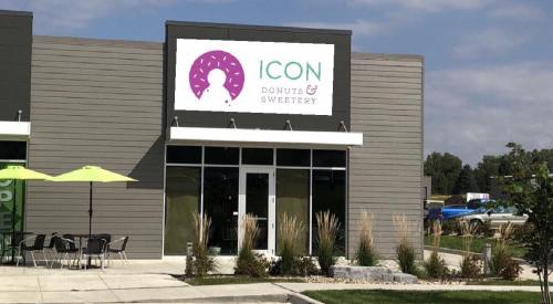 Exterior of a modern donut shop named "Icon Donuts & Sweetery," featuring a large sign and outdoor seating.