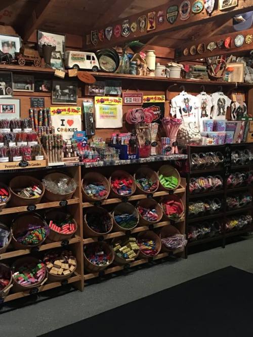 A cozy candy shop interior with colorful jars, baskets of sweets, and vintage decor on the walls.
