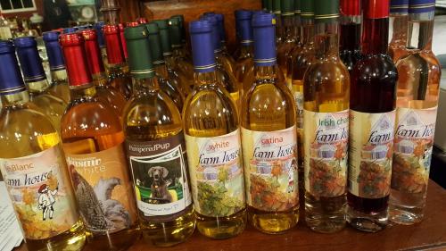 A variety of wine bottles with colorful labels, displayed on a wooden shelf in a cozy setting.