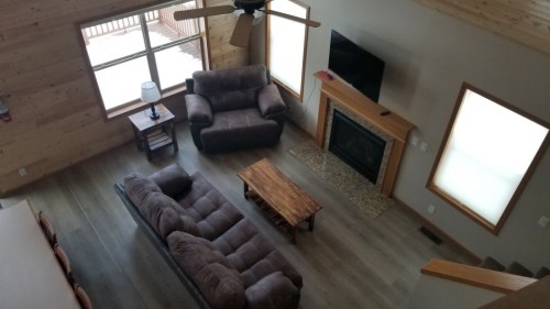 Cozy living room with a brown sofa, wooden coffee table, fireplace, and large windows letting in natural light.