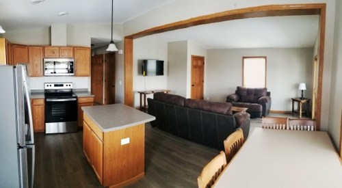A spacious kitchen and living area with wooden cabinets, a dining table, and comfortable seating.