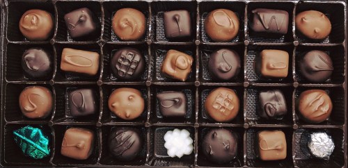 A box of assorted chocolates featuring various shapes and designs, including dark and milk chocolate pieces.