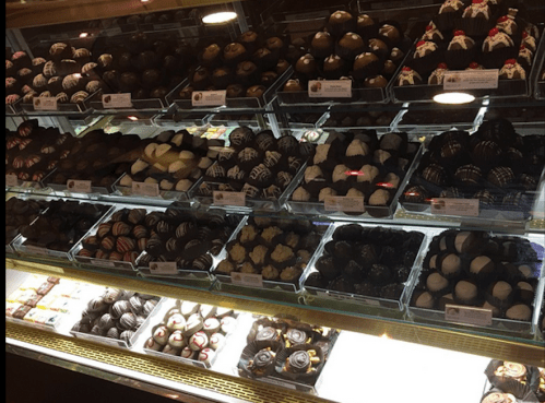 A display case filled with various types of chocolates and truffles in an assortment of shapes and colors.