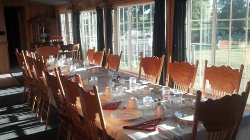A long dining table set for a meal, with wooden chairs and large windows letting in natural light.