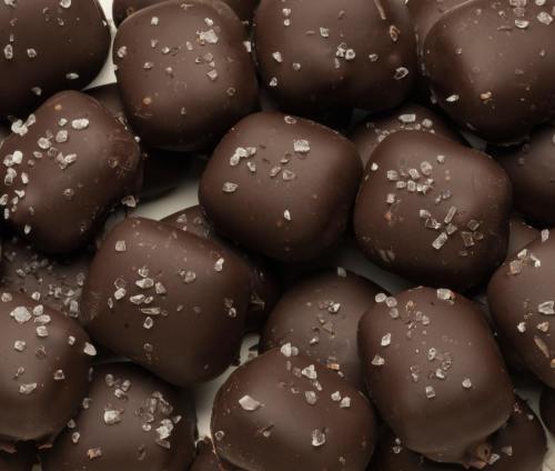 A close-up of dark chocolate-covered treats sprinkled with coarse sea salt.