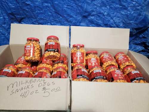Two cardboard boxes filled with jars of Milk-Bone dog snacks, labeled 40 oz, priced at $5 each.