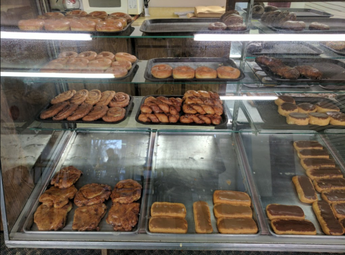 A display case filled with various baked goods, including cinnamon rolls, donuts, and pastries.