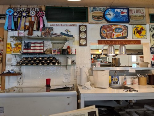 A cozy diner interior with awards, vintage signs, and a BBQ menu displayed on the wall.