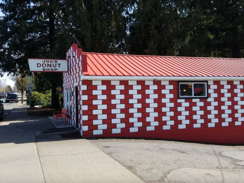 A red and white checkered building with a sign reading "Joe's Donut Shop" and an "Open" sign in the window.