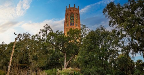 The top of the Bok Tower in Lake Wales, Florida, surrounded by trees and lush bushes