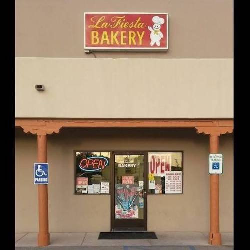 Exterior of La Fiesta Bakery with a bright sign, open door, and visible parking signs.